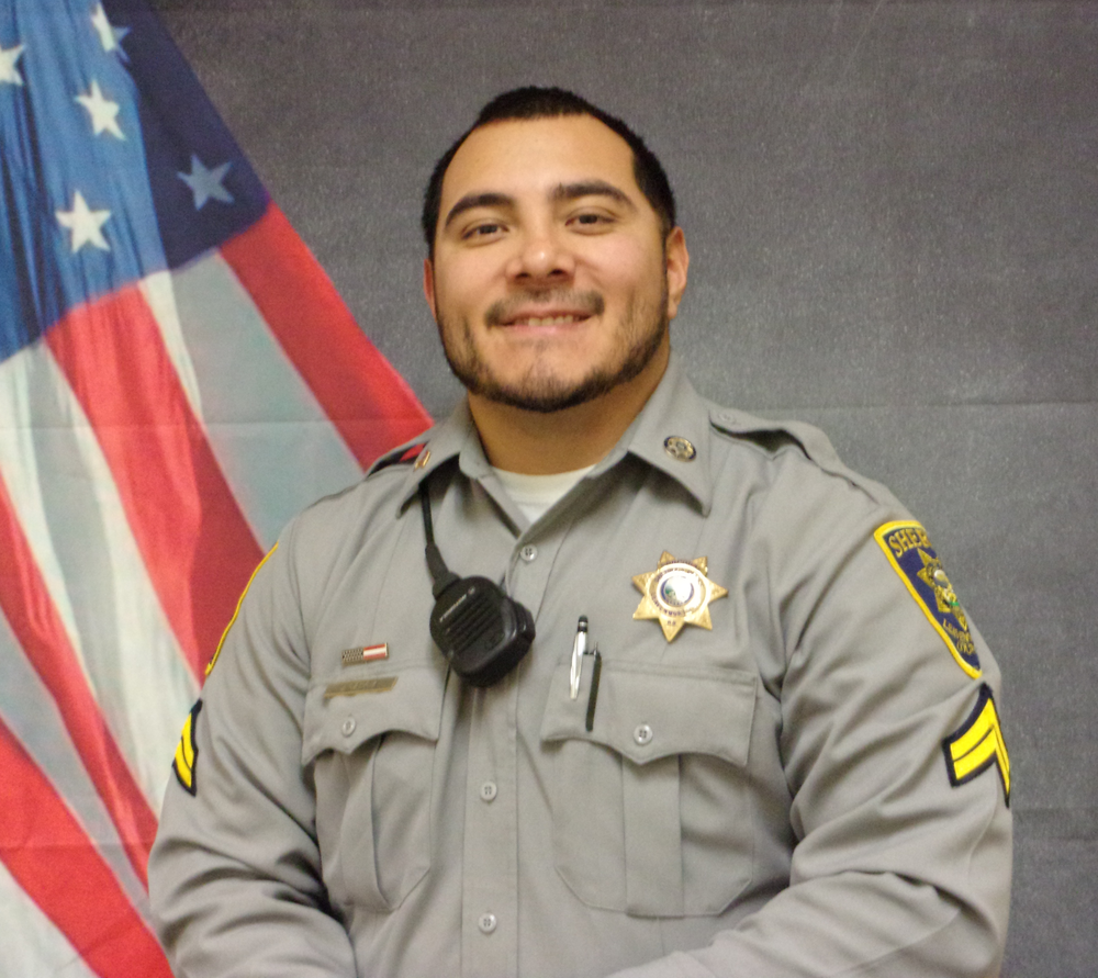 formal picture of sergeant francisco garcia in grey sheriff's office uniform and American flag background